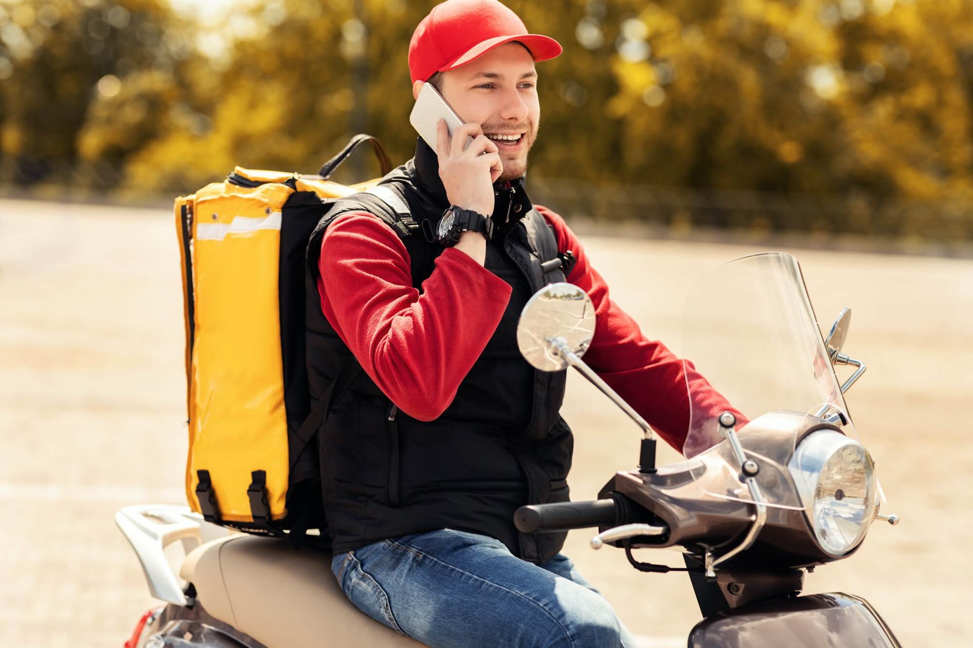 courier-talking-on-mobile-phone-sitting-on-scooter-in-city-1.jpg