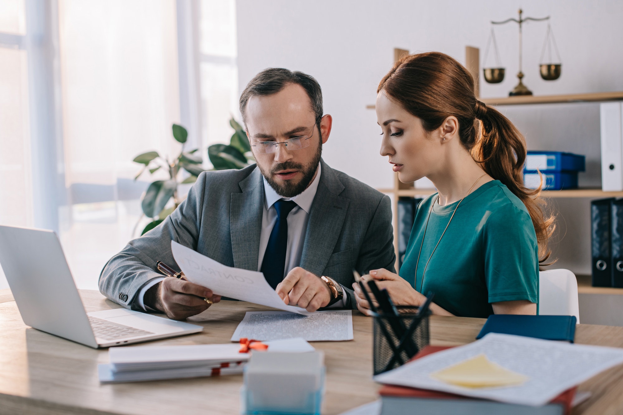 lawyer-and-client-discussing-contract-at-workplace-with-laptop-in-office.jpg