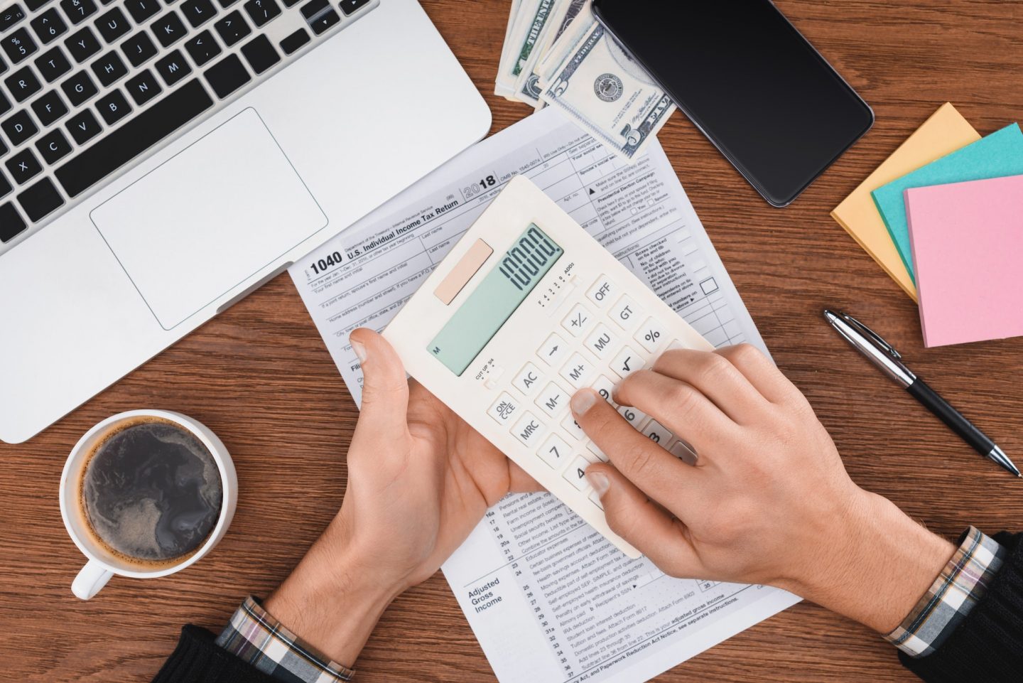 cropped-view-of-man-using-calculator-with-tax-form-and-laptop-on-background-e1670796449877.jpg