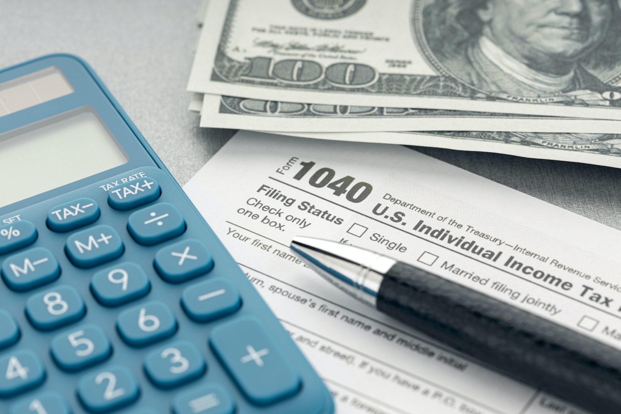 tax-form-calculator-money-and-pen-on-table.jpg